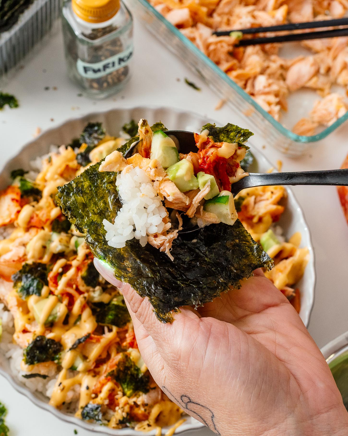 A crispy seaweed snack wrapped around a warm, saucy bite of salmon rice