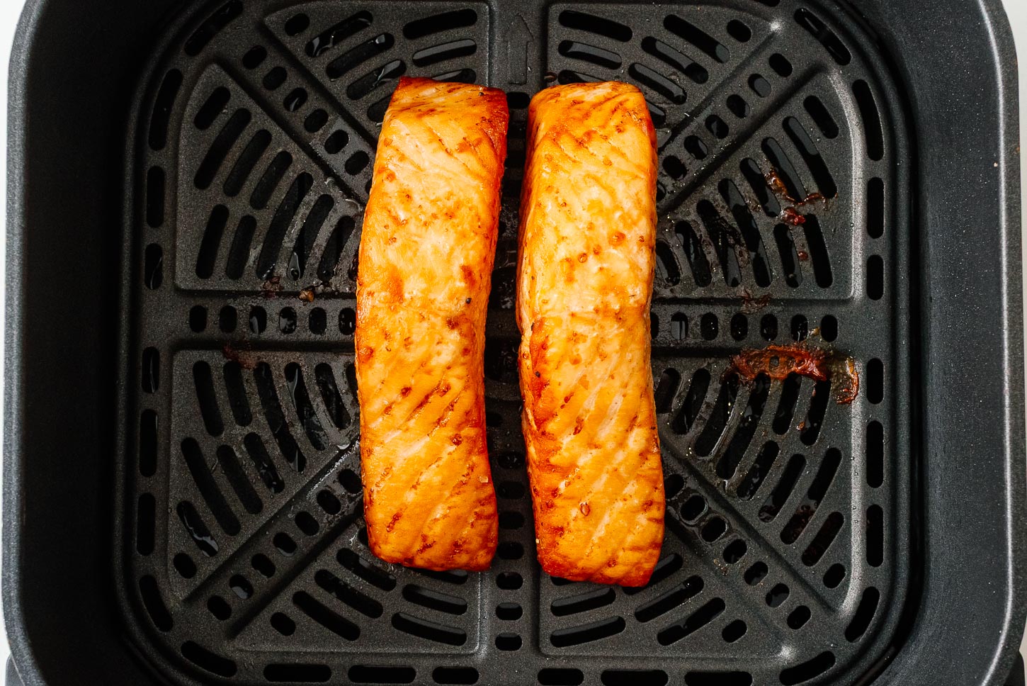 Two salmon fillets, golden and a little crispy at the edges, fresh out of the air fryer